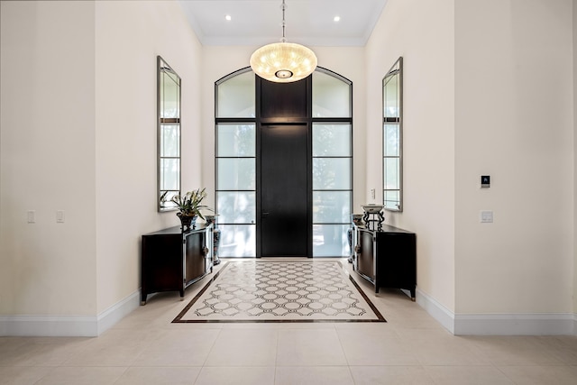 tiled foyer entrance featuring plenty of natural light, a chandelier, and ornamental molding