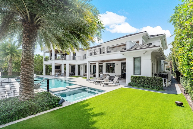 back of house with a patio, a balcony, a lawn, and a pool with hot tub