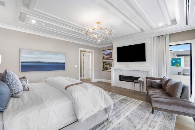 bedroom with a fireplace, light wood-type flooring, crown molding, and a chandelier