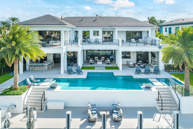 rear view of property featuring a balcony, an outdoor bar, and a patio