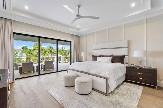 bedroom with ceiling fan, a tray ceiling, access to outside, and light hardwood / wood-style flooring