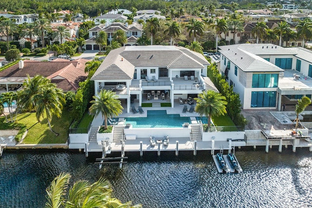 back of property with a patio area, a balcony, and a water view