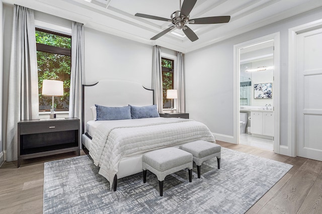 bedroom with connected bathroom, light hardwood / wood-style flooring, ceiling fan, and ornamental molding