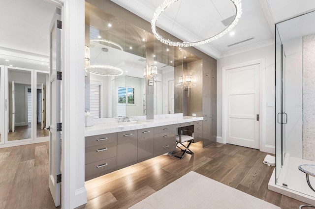 bathroom with crown molding, vanity, wood-type flooring, and an enclosed shower