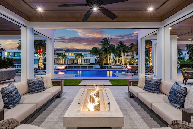 patio terrace at dusk with ceiling fan and an outdoor living space with a fire pit