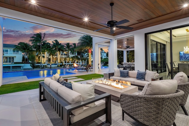 patio terrace at dusk with ceiling fan and an outdoor living space with a fire pit