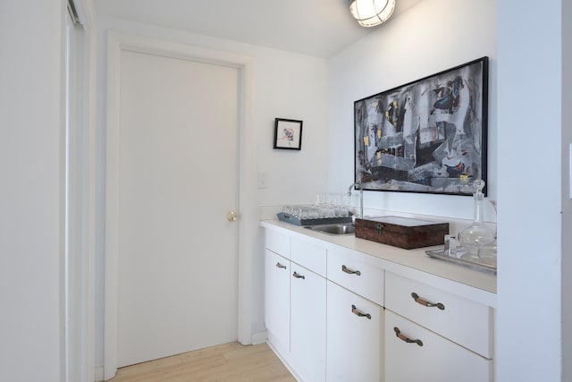 interior space featuring light hardwood / wood-style flooring, white cabinetry, and sink