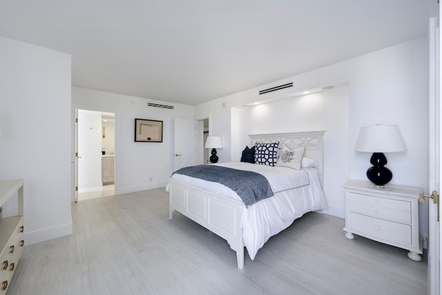 bedroom featuring connected bathroom and light hardwood / wood-style floors