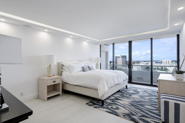 bedroom with access to outside, light hardwood / wood-style flooring, and a wall of windows