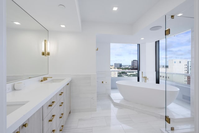 bathroom featuring plenty of natural light, a bath, vanity, and tile walls