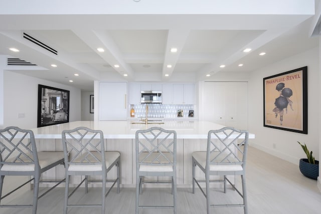 kitchen featuring a kitchen bar, white cabinetry, sink, and a large island with sink