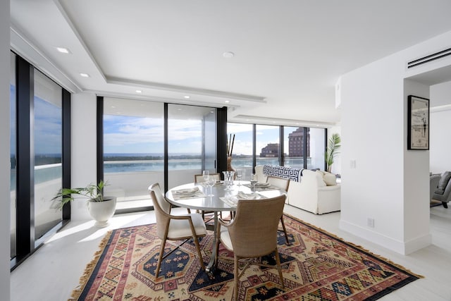 dining room featuring a water view and a wall of windows