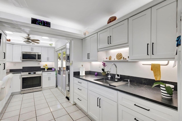 kitchen with stainless steel appliances, ceiling fan, sink, white cabinets, and light tile patterned flooring