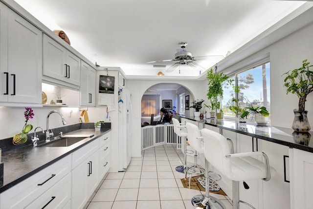 kitchen with ceiling fan, white cabinetry, light tile patterned floors, and sink