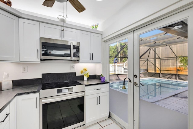 kitchen featuring white range with electric stovetop, white cabinetry, ceiling fan, and light tile patterned floors