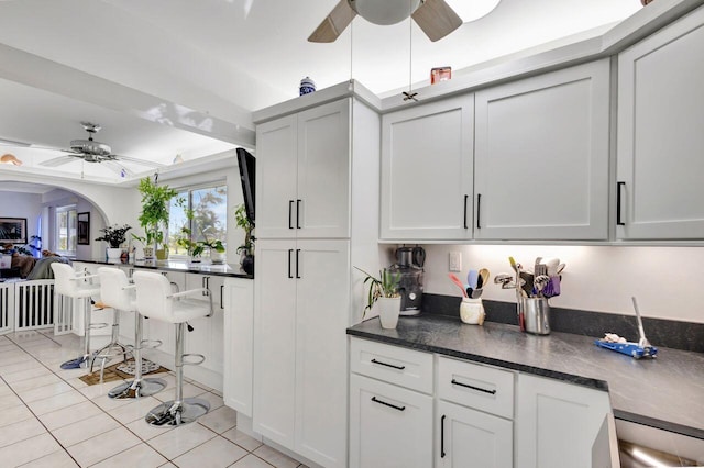 interior space with white cabinets, light tile patterned floors, and ceiling fan