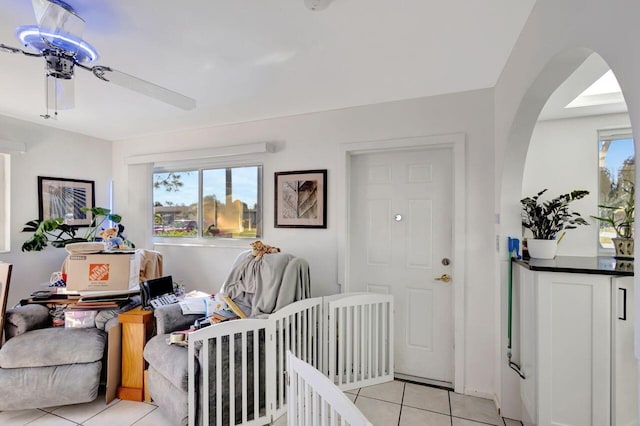 bedroom with ceiling fan, light tile patterned flooring, and a nursery area