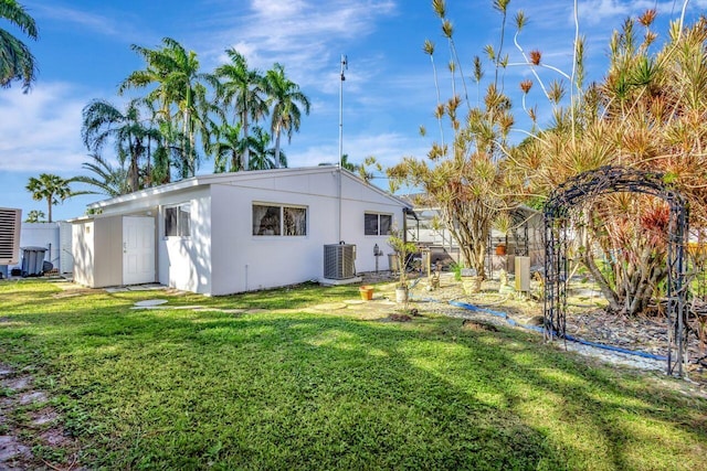 rear view of house featuring central air condition unit and a yard