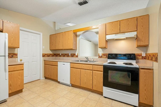 kitchen with a textured ceiling, white appliances, and sink