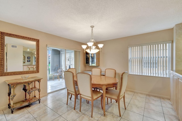 dining area with visible vents, a textured ceiling, a chandelier, and light tile patterned flooring