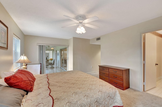 bedroom featuring visible vents, baseboards, light carpet, a textured ceiling, and a ceiling fan