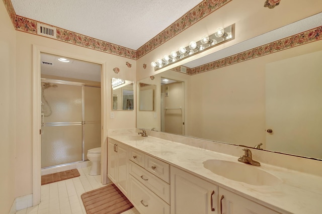 full bathroom with toilet, a sink, a textured ceiling, a shower stall, and double vanity