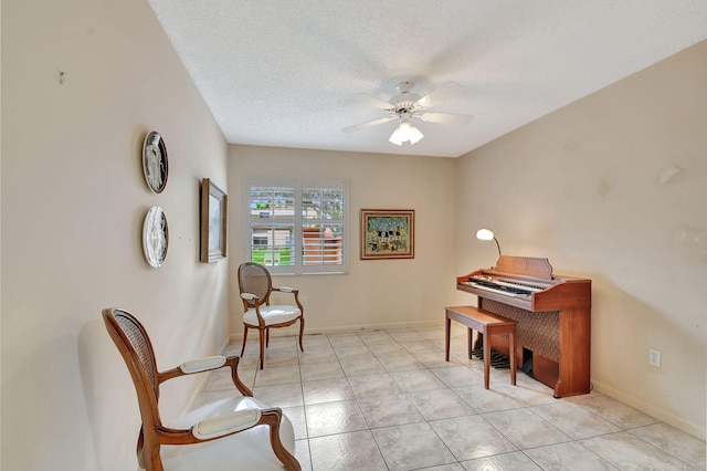 sitting room featuring light tile patterned floors, baseboards, a textured ceiling, and ceiling fan