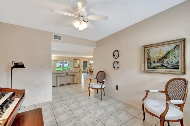 sitting room with visible vents, a textured ceiling, light tile patterned flooring, baseboards, and ceiling fan