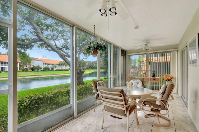 sunroom with a ceiling fan and a water view