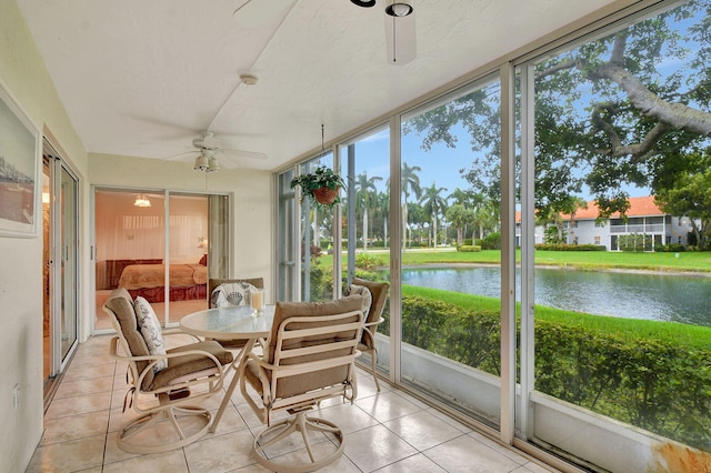 sunroom featuring a ceiling fan and a water view