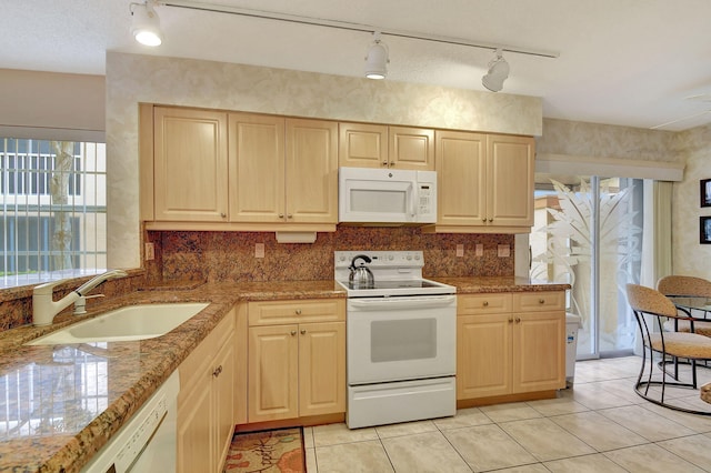 kitchen featuring light brown cabinetry, decorative backsplash, white appliances, and a sink