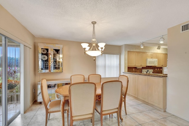 dining room with light tile patterned floors, a notable chandelier, a wealth of natural light, and a textured ceiling