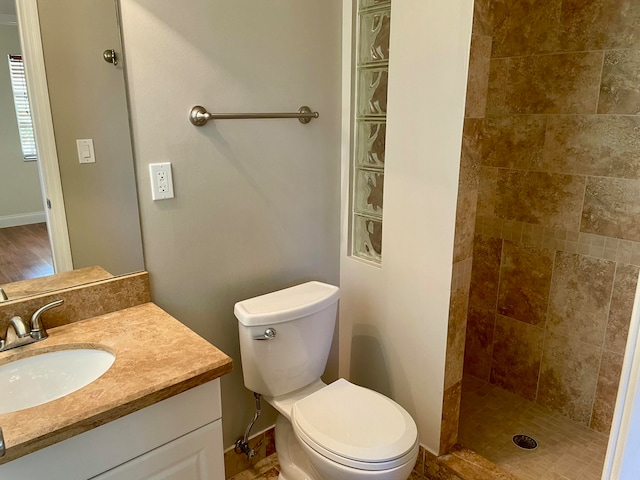 bathroom with vanity, toilet, wood-type flooring, and tiled shower