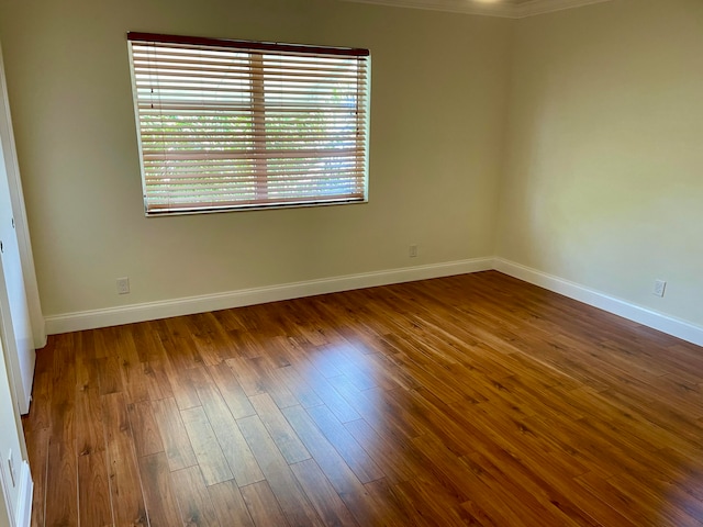 empty room with hardwood / wood-style flooring and crown molding