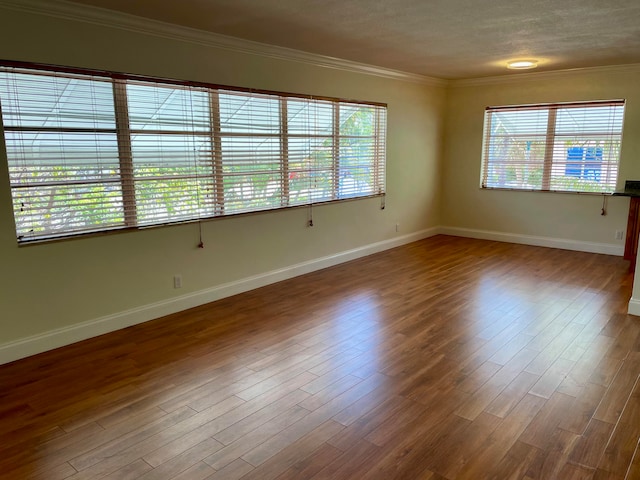 empty room featuring hardwood / wood-style floors, crown molding, and a textured ceiling