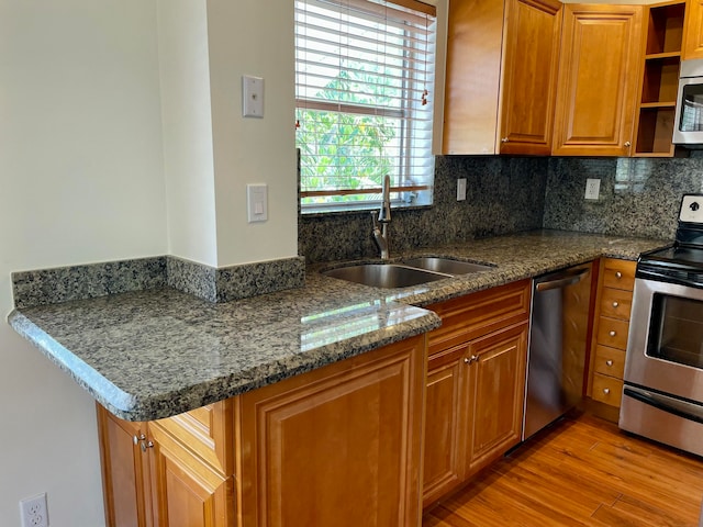 kitchen featuring sink, light hardwood / wood-style flooring, decorative backsplash, appliances with stainless steel finishes, and kitchen peninsula