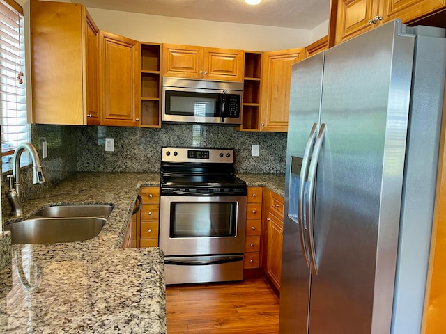 kitchen featuring stone counters, stainless steel appliances, light hardwood / wood-style flooring, and sink