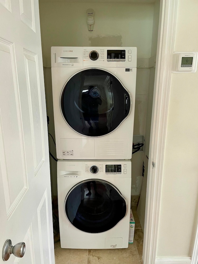 laundry room with light tile patterned floors and stacked washer / dryer