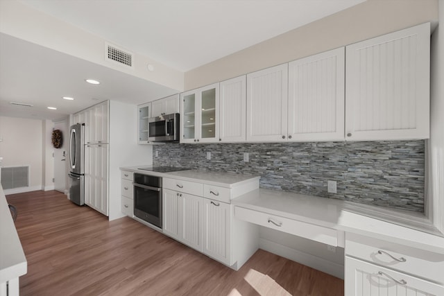 kitchen featuring backsplash, white cabinets, stainless steel appliances, and light hardwood / wood-style floors