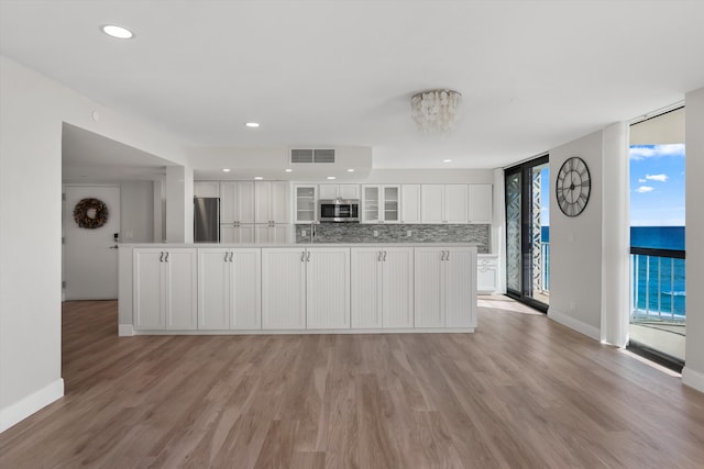 kitchen with white cabinetry, a water view, stainless steel appliances, and light hardwood / wood-style floors