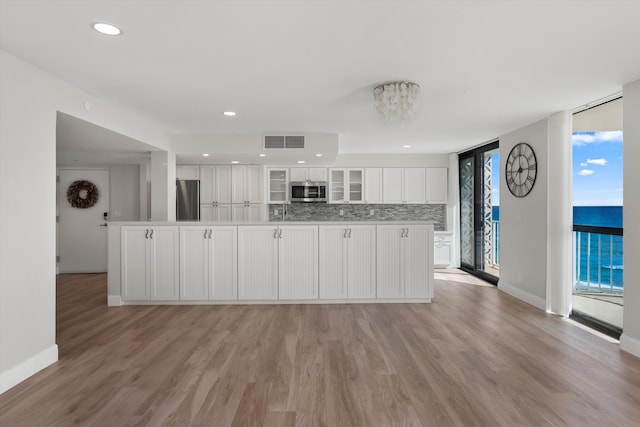 3400 S Ocean Blvd Unit 3Fii, Palm Beach, FL 33480 - kitchen with stainless steel appliances, white cabinetry, light wood-style flooring, glass insert cabinets, and tasteful backsplash