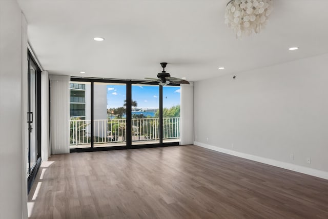 unfurnished room with hardwood / wood-style flooring, ceiling fan, and a wall of windows