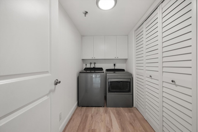 laundry area with washer and dryer, cabinets, and light hardwood / wood-style flooring