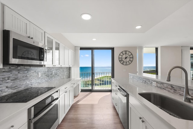 kitchen with white cabinets, appliances with stainless steel finishes, a water view, and sink