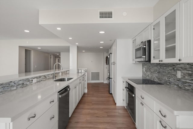 kitchen featuring backsplash, dark wood-type flooring, white cabinets, sink, and appliances with stainless steel finishes