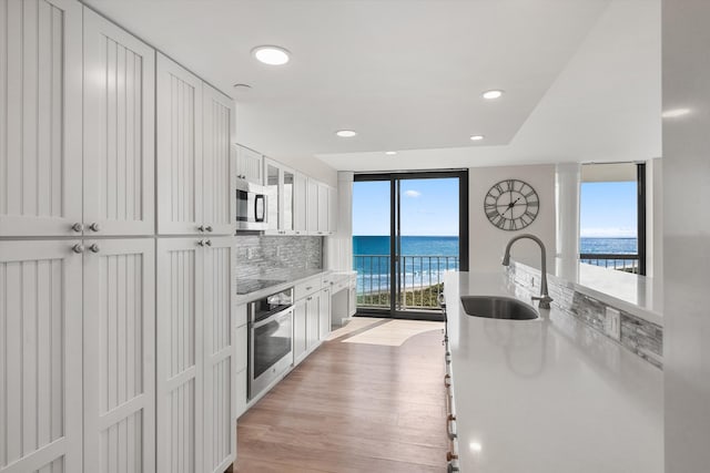3400 S Ocean Blvd Unit 3Fii, Palm Beach, FL 33480 - kitchen with appliances with stainless steel finishes, a water view, white cabinetry, light countertops, and decorative backsplash