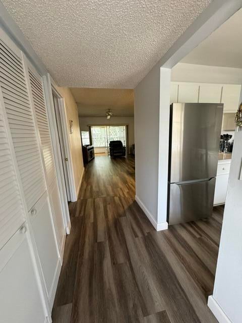 hall featuring a textured ceiling and dark wood-type flooring