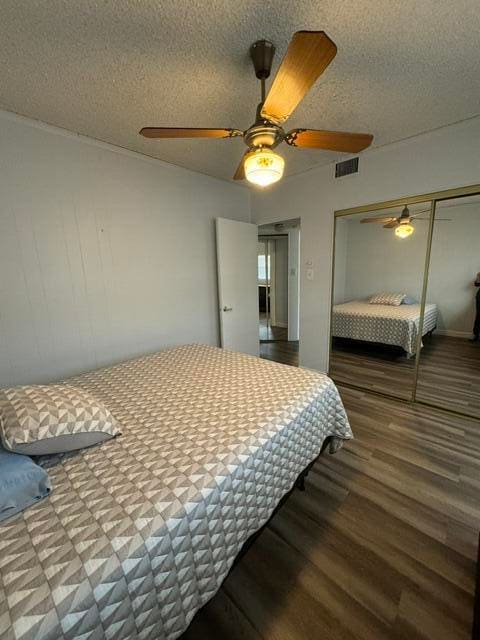 bedroom featuring hardwood / wood-style floors, a textured ceiling, a closet, and ceiling fan