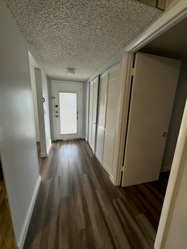 hall with dark hardwood / wood-style flooring and a textured ceiling