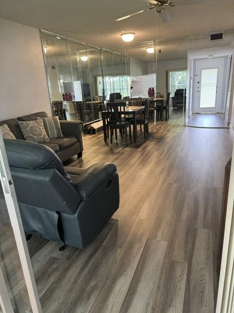 living room featuring hardwood / wood-style floors, a textured ceiling, and ceiling fan